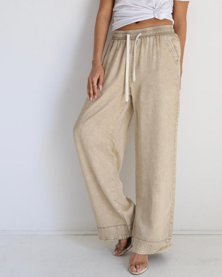 Woman wearing a white top and beige pants against a white background