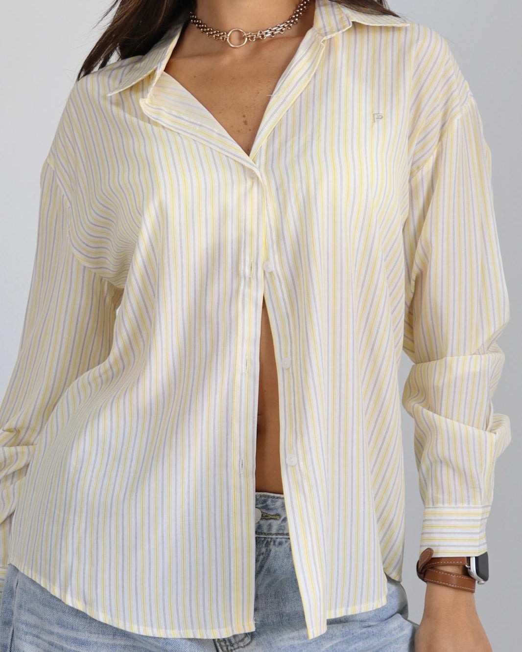 Woman wearing a white and yellow striped shirt with a gray background