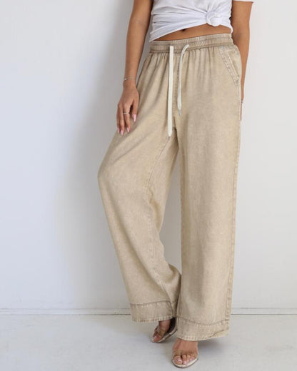 Woman wearing a white top and beige pants against a white background