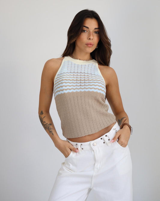 Woman wearing a two-tone crop top and white pants on a plain background